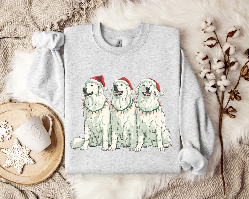 3 big white fluffy dogs sit together with christmas hats on their heads and christmas lights for collars