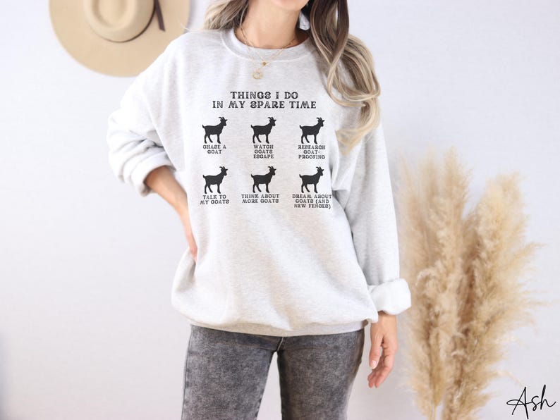 May include: A light gray sweatshirt with the text "THINGS I DO IN MY SPARE TIME" and goat illustrations. The text includes phrases like "GRAZE A GOAT", "WATCH GOATS ESCAPE", and "TALK TO MY GOATS".