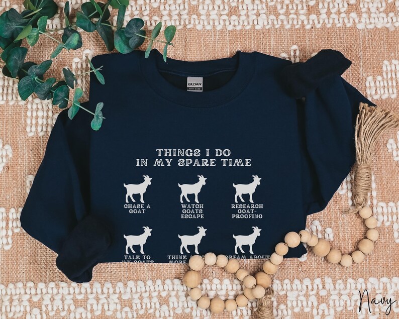 May include: Navy blue sweatshirt with white text and goat illustrations. The text reads "THINGS I DO IN MY SPARE TIME" with phrases like "CHASE A GOAT" and "DREAM ABOUT GOATS". The word "Navy" is at the bottom right.