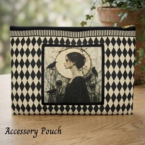 May include: A rectangular accessory pouch featuring a black and cream diamond pattern. The center displays a square illustration of a person in profile against a large moon, surrounded by bare branches and black birds, with a gold-tone zipper.