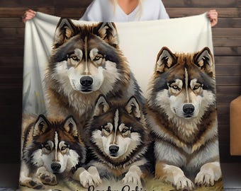 Puede incluir: Una manta suave de color crema con una ilustración detallada en acuarela de cuatro lobos. Los lobos tienen pelaje marrón, gris y blanco, con ojos amarillos penetrantes. La manta tiene el texto "Landry Cabin" en una fuente cursiva.