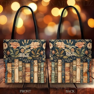 May include: A tote bag with a dark blue background featuring a floral design and a row of books. The bag has black handles and the initials "BKL" are displayed on the front and back. The floral design includes roses and other flowers.
