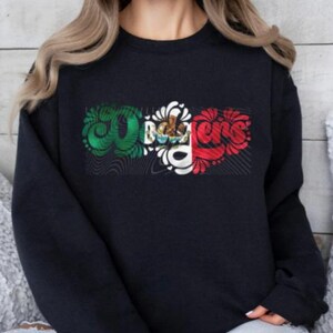 May include: Black sweatshirt featuring a graphic design of the word "Ole" in a stylised font with the colours of the Mexican flag.