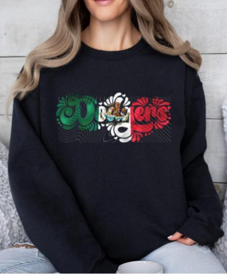 May include: Black sweatshirt featuring a graphic design of the word "Ole" in a stylised font with the colours of the Mexican flag.