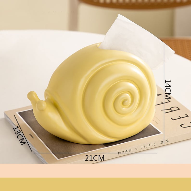 Puede incluir: Un porta pa&ntilde;uelos de cer&aacute;mica amarillo con forma de caracol. El porta pa&ntilde;uelos mide 14 cm de alto, 21 cm de ancho y 13 cm de profundidad.