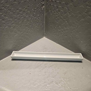 May include: A long, narrow, rectangular white ceramic tray with a smooth, glossy finish and slightly raised edges. The tray features a simple, clean design with a flat base and open top, suitable for holding small items or serving narrow food.