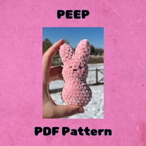 May include: A pink crocheted Peep plush toy with black eyes and a black mouth. The toy is being held in a hand against a snowy background. The text "PEEP" is at the top of the image and "PDF Pattern" is at the bottom of the image.