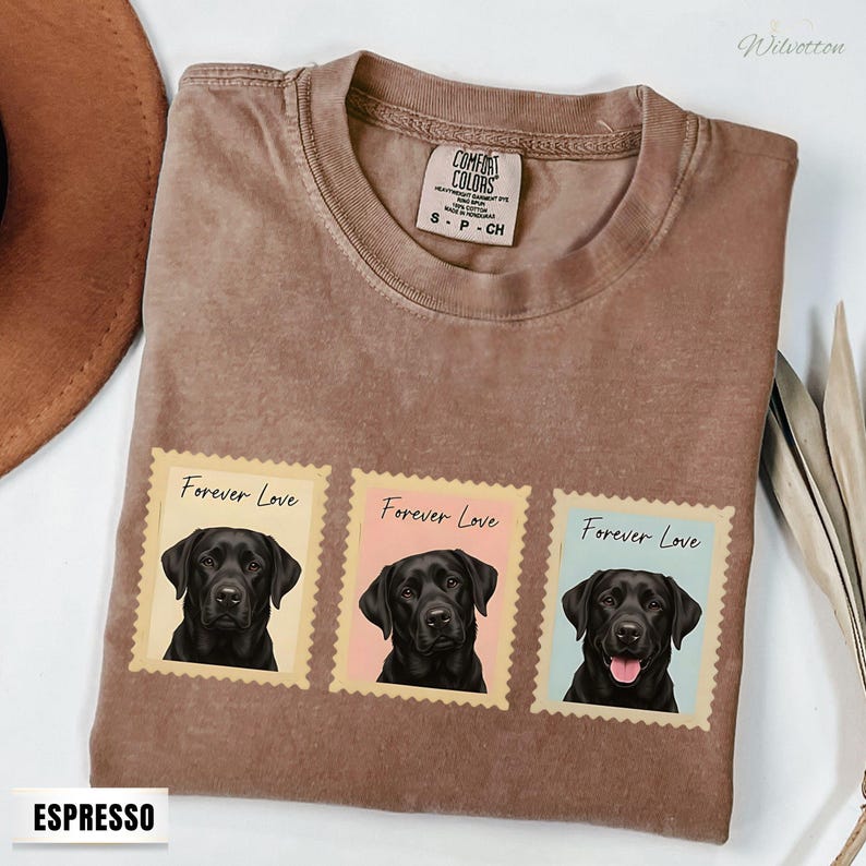 May include: Espresso-coloured t-shirt with three postage stamp designs. Each stamp features a black Labrador portrait and the words "Forever Love." The shirt has a crew neck and a Comfort Colors tag. The word "Espresso" is printed at the bottom.