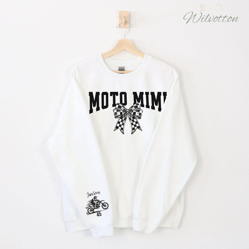 May include: White sweatshirt with the text "MOTO MIMI" in black block letters, a checkered bow graphic, and a motorcycle graphic with the name "Jaxson" and the number "45".