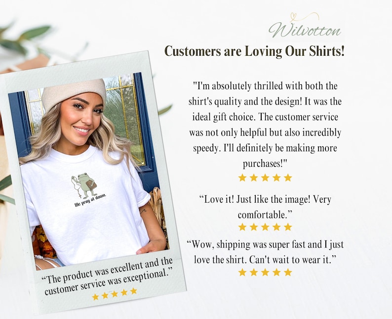 May include: A white t-shirt featuring a small graphic of a green frog holding a white flower and a brown book with the text 'we pray at dawn' underneath. The shirt is displayed in a polaroid-style frame alongside customer reviews and five-star ratings.