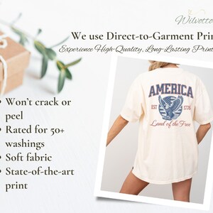 Puede incluir: Una camiseta blanca con un estampado gr&aacute;fico azul y rojo de un &aacute;guila con el texto "AMERICA EST 1776 Land of the Free".