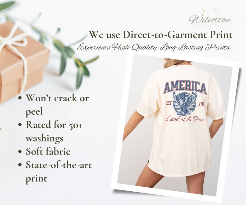 Puede incluir: Una camiseta blanca con un estampado gr&aacute;fico azul y rojo de un &aacute;guila con el texto "AMERICA EST 1776 Land of the Free".