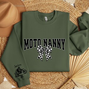 May include: Olive green sweatshirt with the text "MOTO NANNY" in black and white, featuring a checkered bow graphic. The left sleeve has a motorcycle graphic and the name "Jaxson" with the number "45".