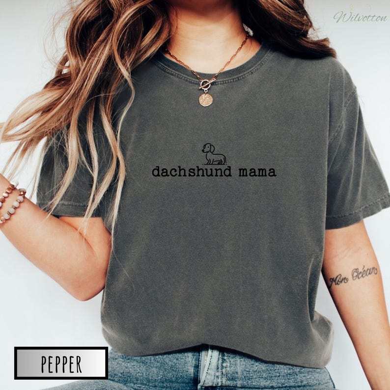 May include: A dark grey t-shirt with a small dachshund silhouette and the text "dachshund mama" printed on the front.