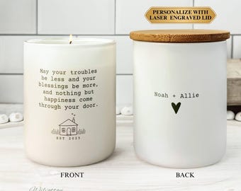 Puede incluir: Dos velas de cerámica blanca con texto y tapa de madera. Una vela tiene el texto "May your troubles be less and your blessings be more..." y un dibujo de una casa. La otra vela tiene los nombres "Noah + Allie" y un corazón.