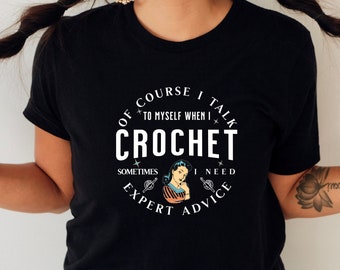 Puede incluir: Camiseta negra con un gráfico circular blanco que dice "Por supuesto que me hablo a mí mismo cuando hago crochet. A veces necesito consejos de expertos."