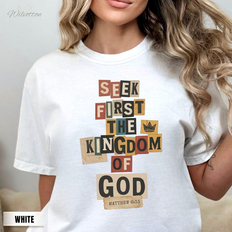 May include: White t-shirt featuring the text "SEEK FIRST THE KINGDOM OF GOD" in a collage style. The text is in various colours and fonts, with a small crown graphic. The text "Matthew 6:33" is below the main text.