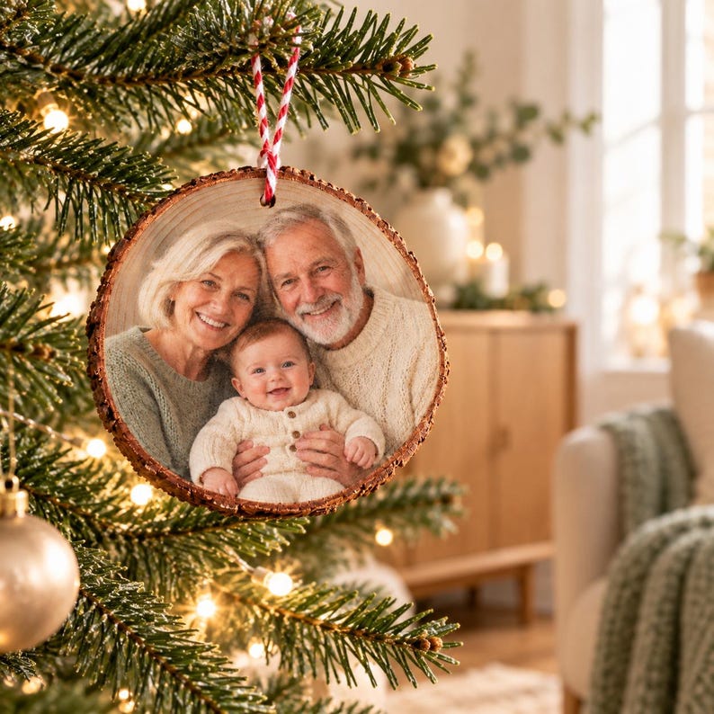 Foto von Oma, Opa und Enkelkind-Fotoanhänger am kleinen Weihnachtsbaum in einem warmen Wohnzimmer mit Sessel und hellem Holz.