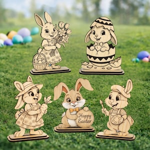 Puede incluir: Figuras de conejos de Pascua de madera en varias poses. Un conejo sostiene flores y una cesta, otro emerge de un huevo, y otros sostienen una zanahoria, un letrero que dice "Happy Easter" y un pincel y una paleta. Sobre un fondo de hierba verde.