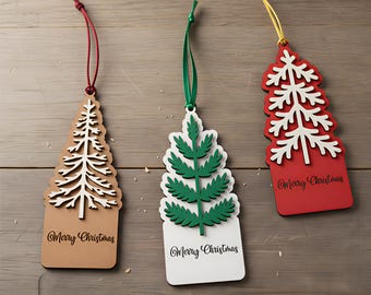 Peut inclure: Trois décorations de Noël en bois en forme de sapins, avec des détails blancs et verts. Le texte "Merry Christmas" est inscrit sur chaque ornement. Chaque décoration est suspendue à un cordon de couleur différente.