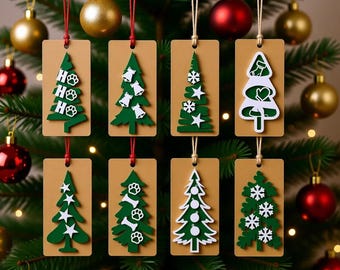 Peut inclure: Une collection de décorations de sapin de Noël suspendues à un arbre vert. Chaque décoration est une étiquette rectangulaire avec un motif de sapin de Noël vert. Certains arbres ont des empreintes de pattes, des cloches ou des étoiles. L'arrière-plan comprend des boules rouges et dorées.