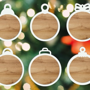 Puede incluir: Seis adornos navide&ntilde;os con marco blanco y dise&ntilde;o de vetas de madera. Cada adorno tiene un dise&ntilde;o superior diferente, incluyendo un lazo, un lazo y una parte superior redondeada. Los adornos est&aacute;n colocados sobre un fondo borroso de luces de &aacute;rbol de Navidad.