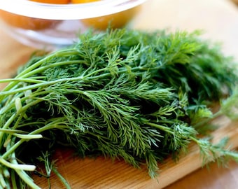 May include: A bunch of fresh green dill sprigs on a wooden cutting board.