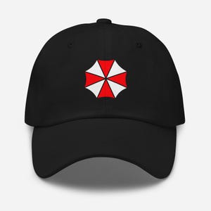 Könnte beinhalten: Schwarze Baseballkappe mit einem rot-weißen Regenschirmlogo. Die Kappe hat einen gebogenen Schirm und ein sechsteiliges Design. Das Logo ist ein stilisierter Regenschirm mit roten und weißen Segmenten.