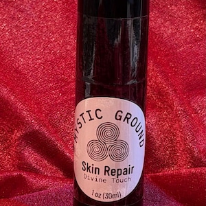 May include: A black cylindrical bottle with a black cap. The bottle has a white label with the words "Mystic Ground" and "Skin Repair Divine Touch" printed on it. The label also includes a graphic of three swirling circles and the text "1 oz (30ml)".