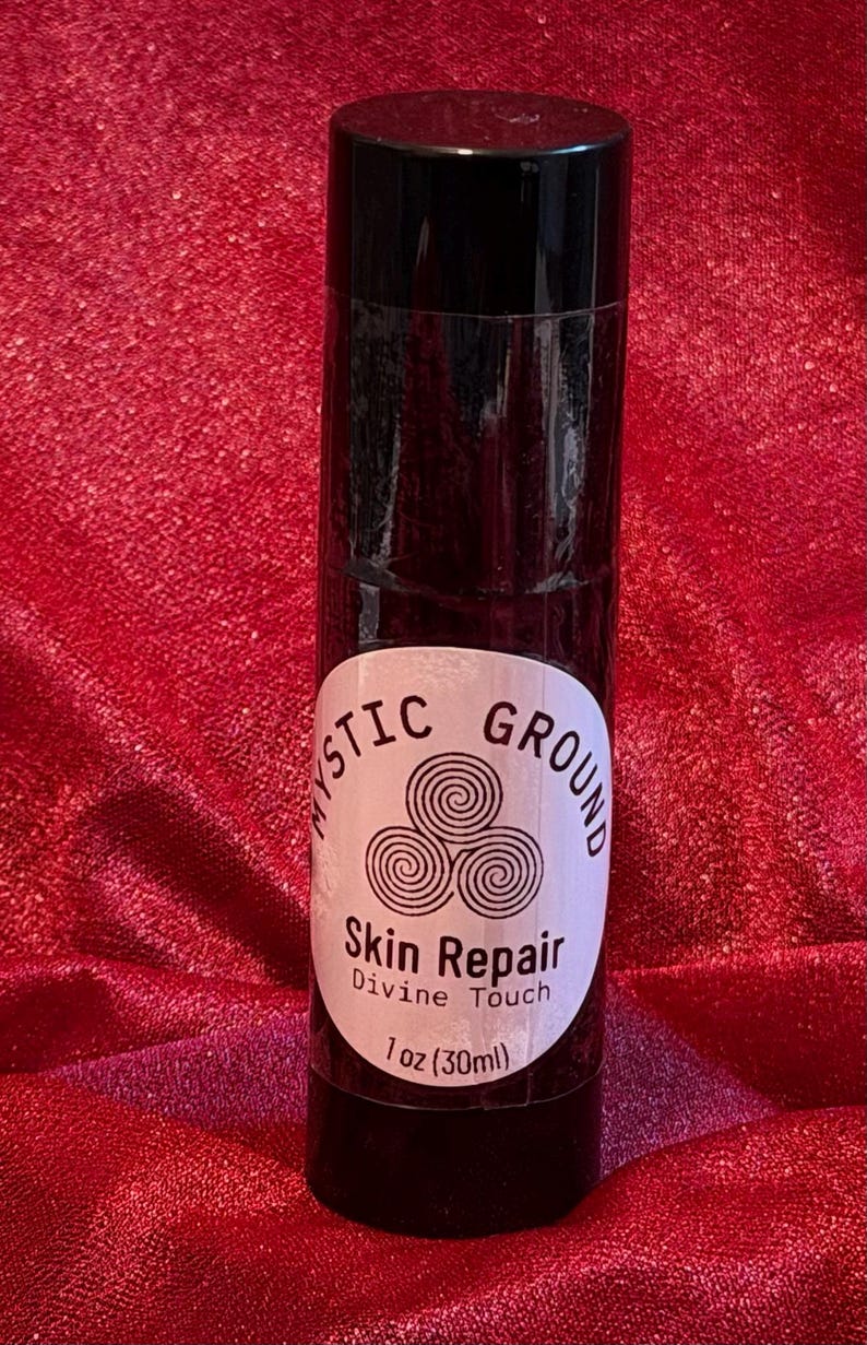 May include: A black cylindrical bottle with a black cap. The bottle has a white label with the words "Mystic Ground" and "Skin Repair Divine Touch" printed on it. The label also includes a graphic of three swirling circles and the text "1 oz (30ml)".