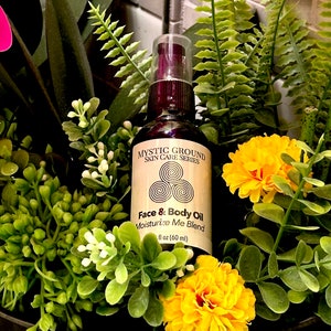 May include: A brown glass bottle with a gold label that reads "MYSTIC GROUND SKIN CARE SERIES Face & Body Oil Moisturize Me Blend 1 fl oz (60 ml)".