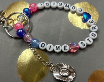 Kacey Musgraves Dime Store Cowgirl-armband med nyckelring och väskberlock med cowboyhattberlock