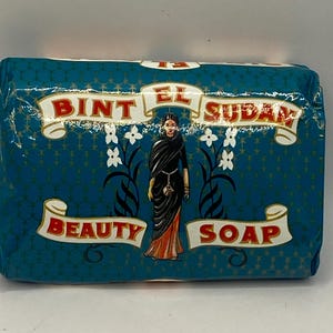 May include: A blue bar of soap with a woman in a colourful sari on the front. The soap is labelled "Bint El Sudan Beauty Soap".