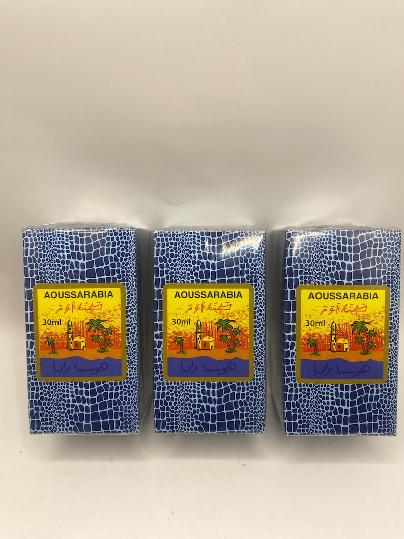 Puede incluir: Tres cajas azules y doradas con un patr&oacute;n de piel de cocodrilo. Cada caja contiene un frasco de 30 ml de perfume Aoussarabia. Las cajas tienen texto &aacute;rabe y las palabras "Aoussarabia" y "30 ml" impresas en ellas.