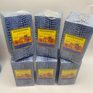 Puede incluir: Seis cajas azules con un patr&oacute;n de piel de cocodrilo. Cada caja contiene un frasco de 30 ml de perfume Aoussarabia. Las cajas tienen texto &aacute;rabe y una imagen de una mezquita y palmeras.