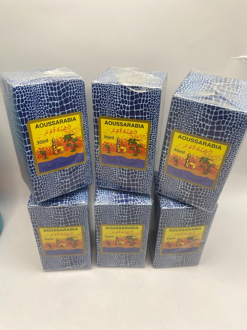 Puede incluir: Seis cajas azules con un patr&oacute;n de piel de cocodrilo. Cada caja contiene un frasco de 30 ml de perfume Aoussarabia. Las cajas tienen texto &aacute;rabe y una imagen de una mezquita y palmeras.