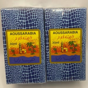Puede incluir: Dos cajas azules y blancas con patrones y bordes dorados. Cada caja contiene un frasco de 30 ml de perfume Aoussarabia. Las cajas presentan una mezquita y palmeras sobre un fondo amarillo. El texto en las cajas dice "Aoussarabia" y "30 ml".