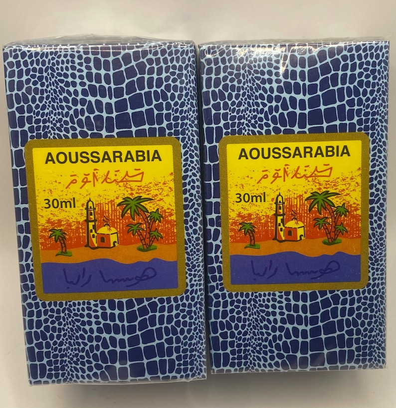 Puede incluir: Dos cajas azules y blancas con patrones y bordes dorados. Cada caja contiene un frasco de 30 ml de perfume Aoussarabia. Las cajas presentan una mezquita y palmeras sobre un fondo amarillo. El texto en las cajas dice "Aoussarabia" y "30 ml".