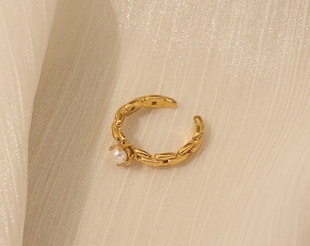 May include: A gold chain ring with a single pearl accent. The ring is open and adjustable.