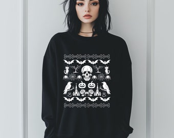 Op de afbeelding: Zwart sweatshirt met een wit Halloween-thema ontwerp. Het ontwerp bevat een schedel, vleermuizen, pompoenen, raven en andere griezelige elementen.