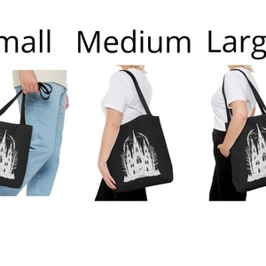 May include: Black tote bag with a white illustration of a gothic cathedral with trees and a crescent moon. The bag is shown in three sizes: small, medium, and large.