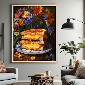 K&ouml;nnte beinhalten: Gerahmter Kunstdruck mit einem Stapel von drei gegrillten K&auml;sesandwiches auf einem blau-wei&szlig;en Teller. Die Sandwiches haben geschmolzenen K&auml;se und sind vor einem Hintergrund aus bunten Blumen platziert.