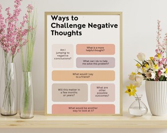 May include: A framed poster titled "Ways to Challenge Negative Thoughts" with text prompts in a beige and peach color scheme. The poster is displayed on a wooden shelf, flanked by vases of pink and yellow flowers.