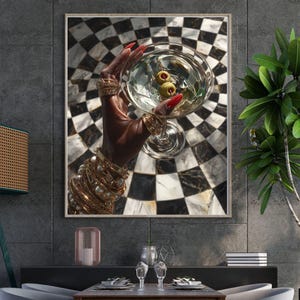 May include: A framed print featuring a hand holding a martini glass with olives. The hand is adorned with gold jewelry and red nail polish. The background has a black and white checkered pattern, creating a stylish and elegant aesthetic.