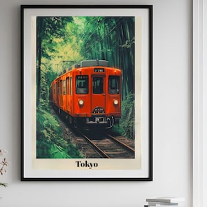 May include: Framed art print featuring an orange train traveling through a lush green forest. The train is the focal point, with the word "Tokyo" at the bottom. The artwork has a vintage, travel poster aesthetic.