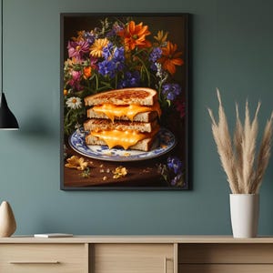 K&ouml;nnte beinhalten: Gerahmter Kunstdruck mit einem Stapel von drei gegrillten K&auml;sesandwiches mit geschmolzenem K&auml;se auf einem blau-wei&szlig;en Teller. Ein lebendiger Blumenstrau&szlig; im Hintergrund.