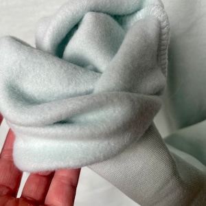 Peut inclure: Gros plan sur un sweat-shirt bleu clair avec un int&eacute;rieur doux et duveteux. Le tissu est pli&eacute; pour montrer l'int&eacute;rieur du v&ecirc;tement.