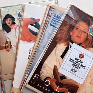 K&ouml;nnte beinhalten: Ein B&uuml;ndel Vintage-Magazinseiten, gesch&uuml;tzt durch Plastikh&uuml;llen. Die Cover zeigen Bilder von Frauen und Text. Eine wei&szlig;e Karte liest "VINTAGE MAGAZINE PAGE BUNDLE" mit "50 PAGES PACK 2 OF 2". Die Zeitschriften haben die W&ouml;rter "RAB" und "FOLIO".