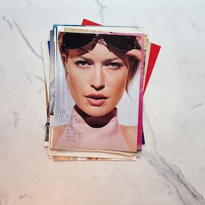 K&ouml;nnte beinhalten: Ein Stapel Zeitschriften, die oberste zeigt eine Frau mit Sonnenbrille. Der Text auf dem Cover lautet: "WE ALWAYS WANT TO SHINE, BUT WE NEVER WANT TO SHINE."