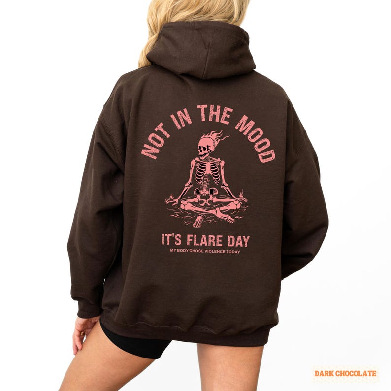 unisex chronic illness hoodie in color dark chocolate. Graphic of a pink skeleton in flames with a phrase not in the mood its flare day in grunge font in pink.